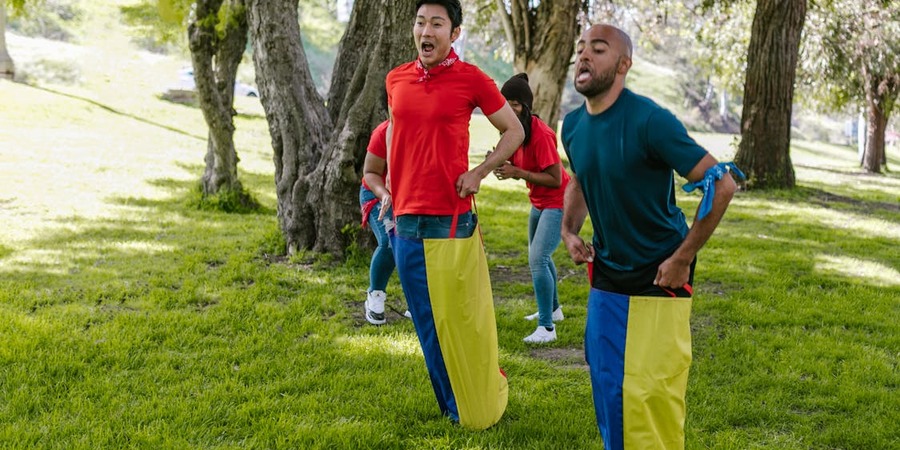 On a beautiful day, friends are jumping in a potato sack race.